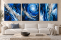 The Trident blue and silver three-piece stretched canvas set without outer frames above an ivory sofa.